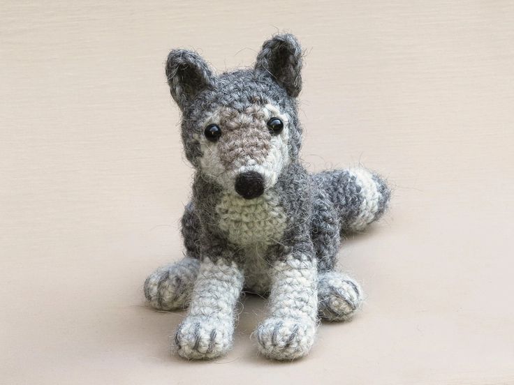 a small gray and white stuffed animal sitting on top of a floor next to a wall