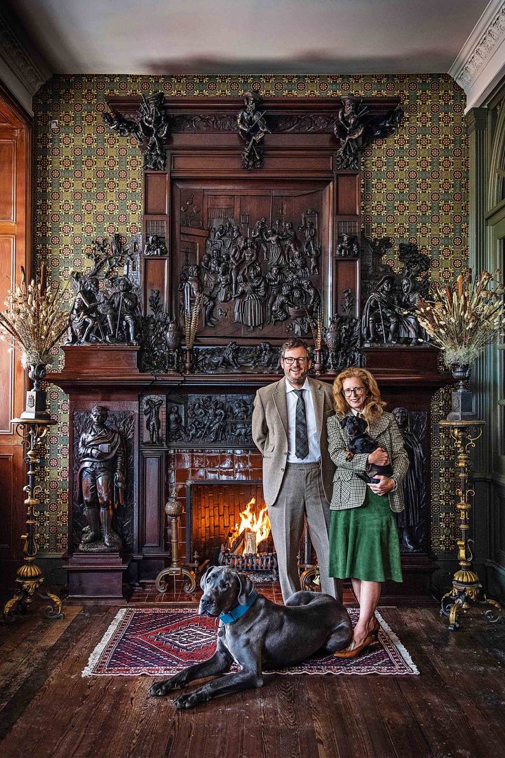 a man and woman standing in front of a fireplace with a dog laying on the floor