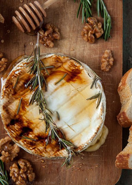 some food is laying out on a cutting board with nuts and honey in the background