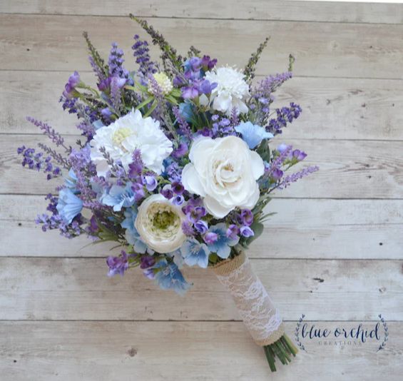 a vase filled with white and blue flowers on top of a wooden floor next to a wall