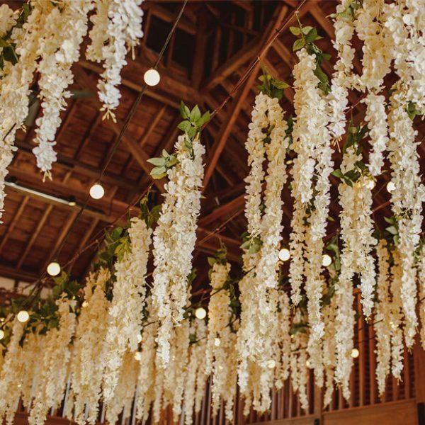 white flowers are hanging from the ceiling in a room with wooden beams and lights on it