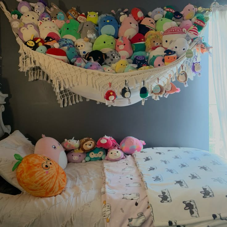 a bed with lots of stuffed animals on top of it and hanging from the ceiling