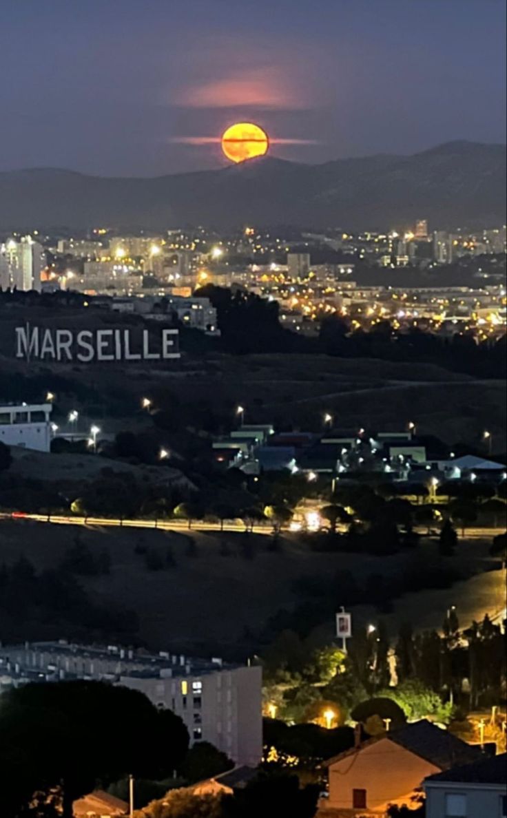 the full moon is seen in the distance over a city