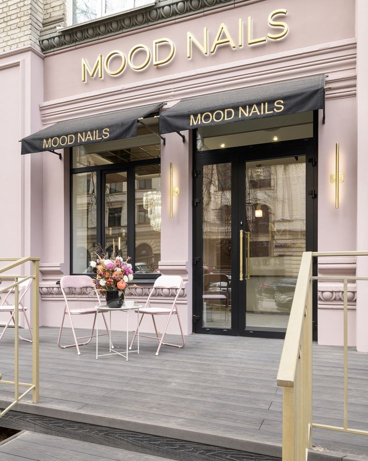 a pink nail salon with chairs and tables outside