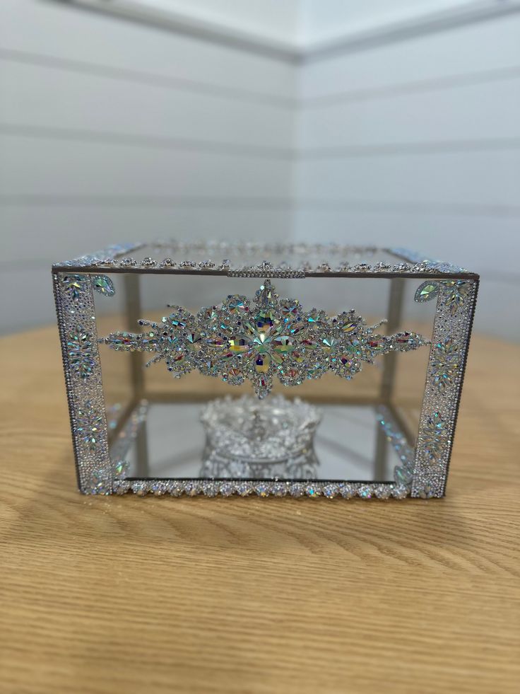 a crystal box with a cross on the top sitting on a wooden table in front of a white wall