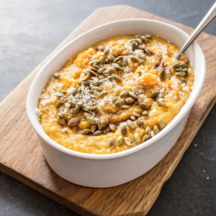 a white bowl filled with food on top of a wooden cutting board