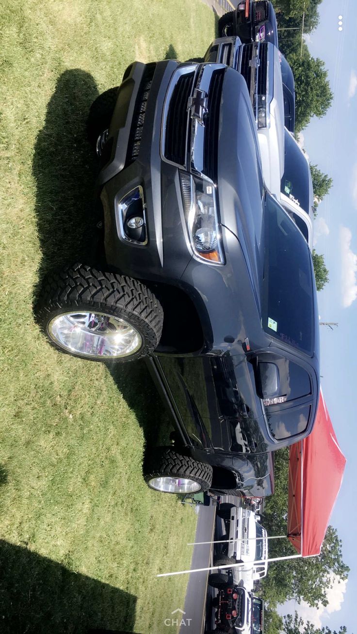 the front end of a black truck parked on top of grass