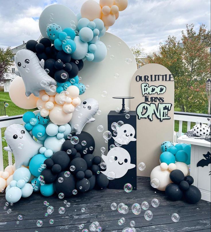 some balloons are floating in the air near a sign and other decorations on a wooden deck