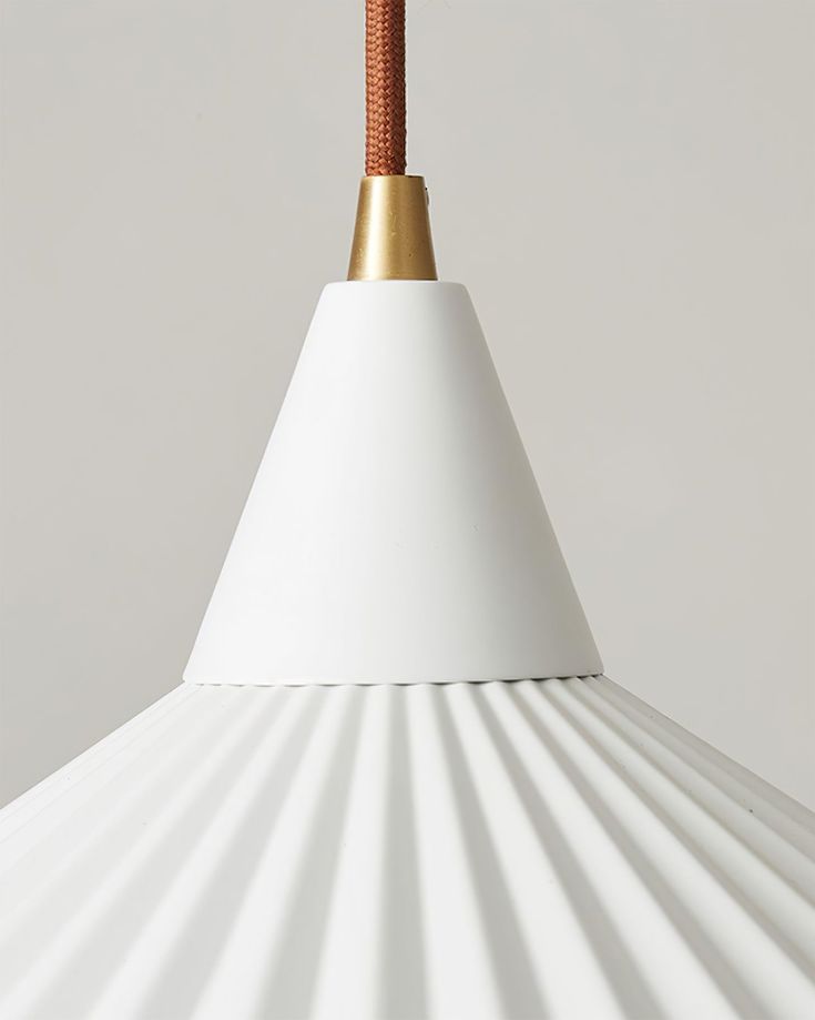 a close up of a white and gold colored lamp with a brown cord attached to it