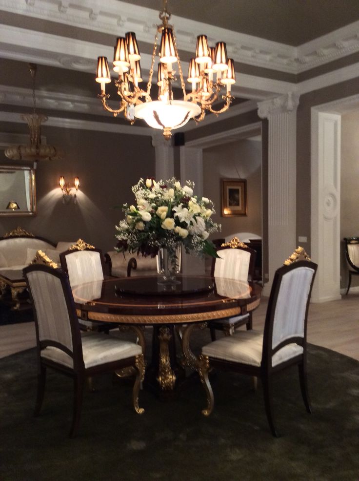 a fancy dining room with chandelier, chairs and flowers on the center table