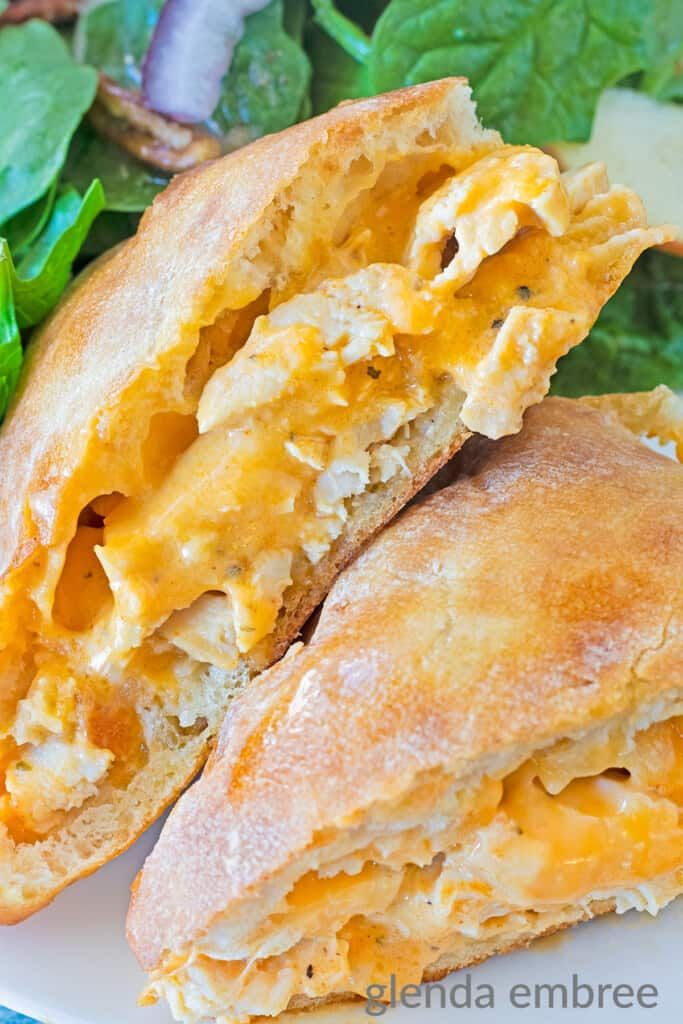 two pieces of bread with cheese and spinach leaves on the side, sitting on a white plate