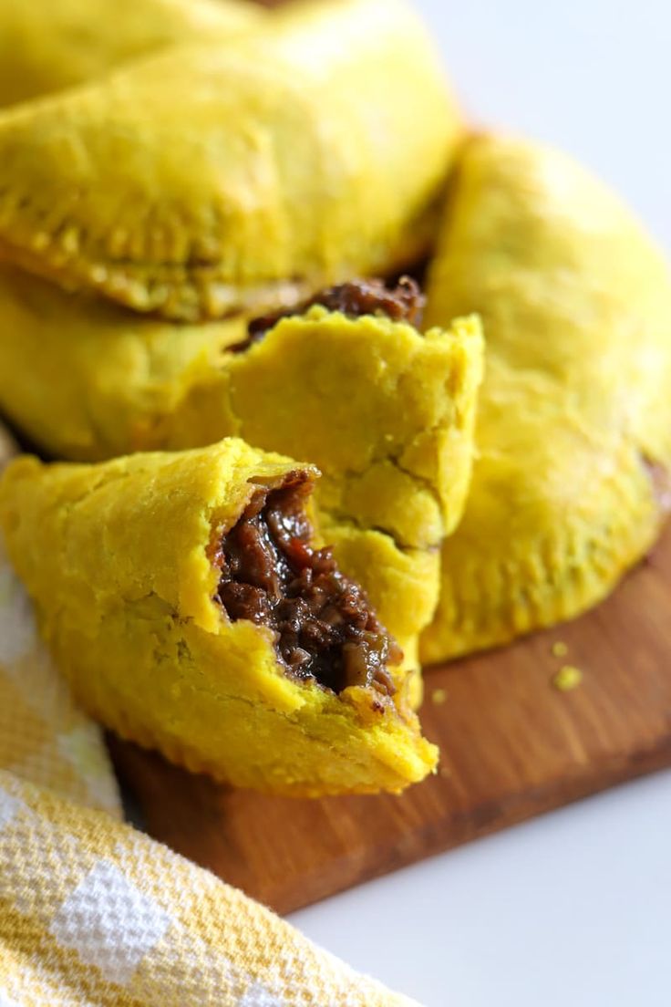 two pastries sitting on top of a wooden cutting board next to a yellow towel