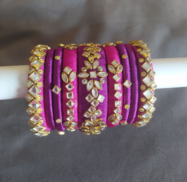 Hey lovely people... Thanks for visiting my shop. Here I have a  very beautiful  silk thread bangles heavily embellished with glass kundans in magenta pink and royal purple colours. Very royal in look. A set of 9 bangles for one hand.  You will receive 18 bangles for both hands.  A must have combo in your wardrobe. Kindly note that the actual colours and sizes of embellishments may vary slightly due to computer screen resolution and I truly hope that you do like my handmade products just as much Royal Purple Color, Silk Thread Bangles Design, Thread Bangles Design, Bridal Gift Wrapping Ideas, Kundan Bangles, Silk Thread Bangles, Silk Thread Jewelry, Thread Bangles, Thread Jewellery