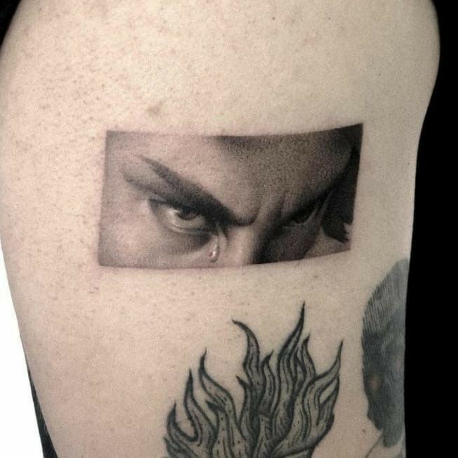 a man's upper arm with an eye and flames on it