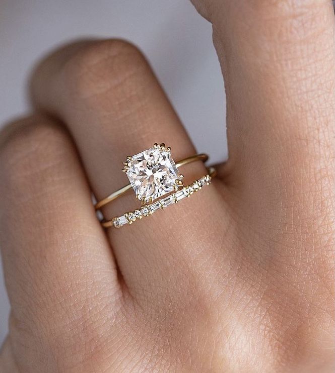 a woman's hand with a diamond ring on top of her finger and an engagement band