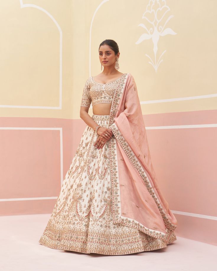 Ivory Raw Silk Lehnga Set | Angad Singh An exquisite ivory double dupatta lehenga set, this ensemble is a masterpiece of traditional zardozi embroidery. Adorned with silken threads, dabka, cutdana, and sequins, it reflects a rich heritage of craftsmanship. The intricate detailing on the lehenga, combined with the elegance of the double dupatta, creates a luxurious and sophisticated look, making it an ideal choice for weddings, festivals, and other special occasions. The subtle yet opulent design ensures you stand out with grace and timeless beauty. Included in Purchase: Lehenga, Blouse and Dupatta Product Specification Color: Ivory Fabric: Raw Silk with Crape Lining Occasion: Wedding, Engagement, Formal Event Designer: Angad Singh Work: Hand Embroidery *Jewelry sold separatelyCustomization Beige Anarkali Set With Gota Work For Wedding, Beige Gota Work Anarkali Set For Wedding, Cream Anarkali Set With Cutdana For Reception, Reception Beige Anarkali Set With Cutdana, White Cutdana Set For Reception, Beige Cutdana Anarkali Set For Reception, Reception Beige Cutdana Anarkali Set, Cream Anarkali Set With Cutdana Detail, Cream Anarkali Set With Cutdana