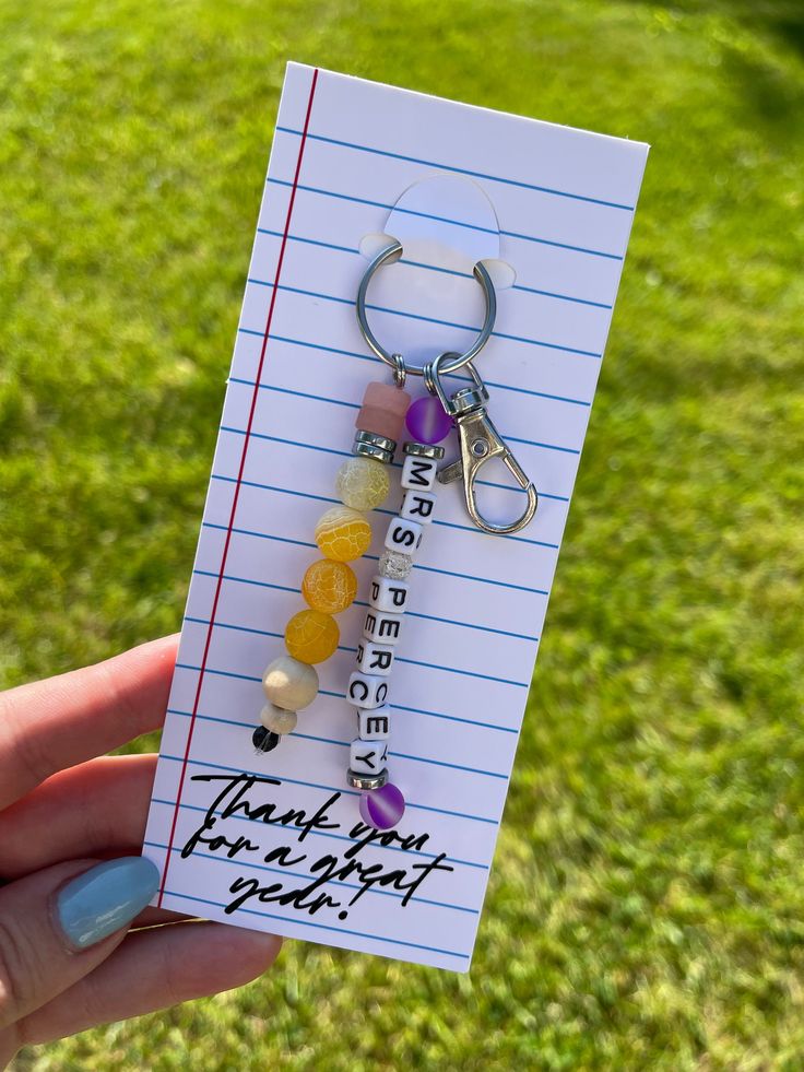 a person holding up a note with a pair of scissors on it and some beads