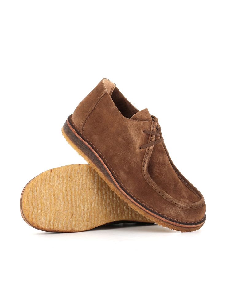 a pair of brown sued shoes on top of a wooden shoe soled foot board