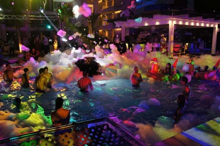 people are playing in the water with colored powder on them and some lights around them