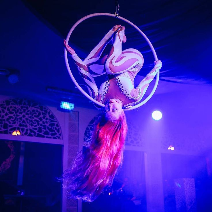 a woman is doing aerial acrobatic tricks on a hoop at a circus