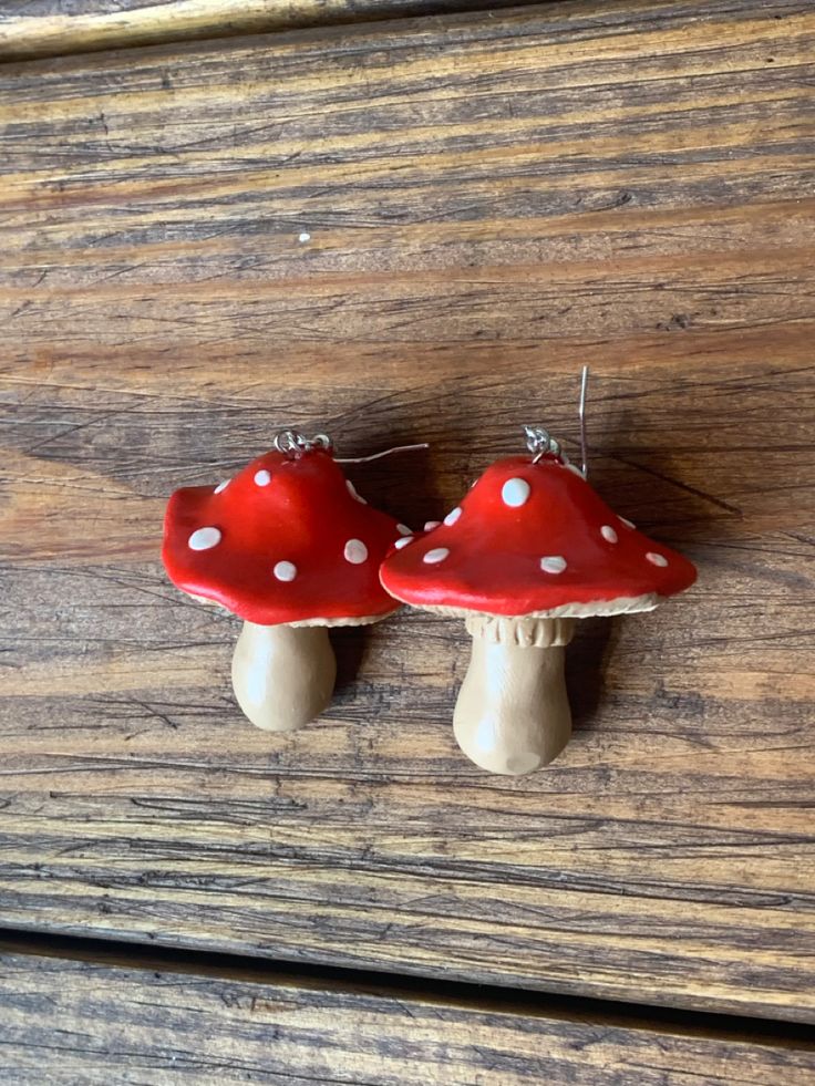 two red mushrooms with white polka dots are hanging from the side of a wooden table