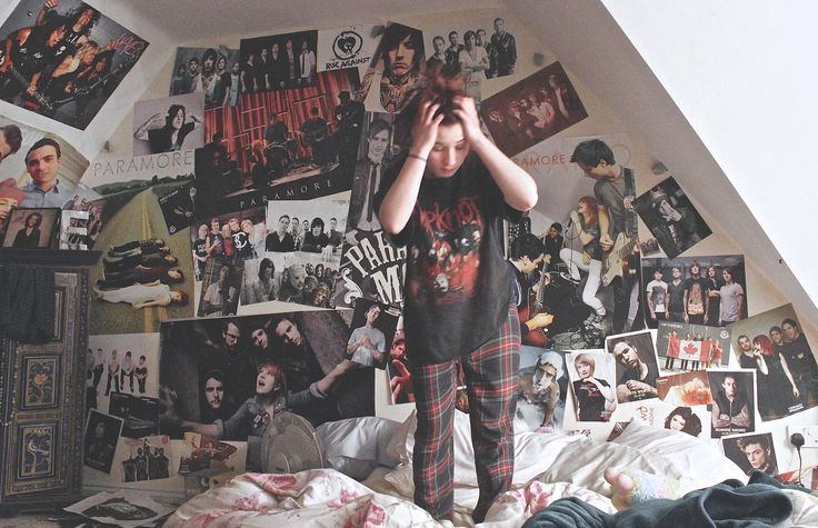 a young boy standing on top of a bed covered in posters