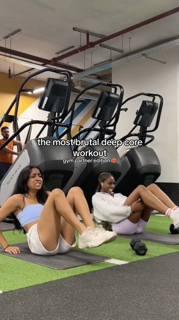 three women sitting on the ground in front of treads and exercise equipment at an indoor gym