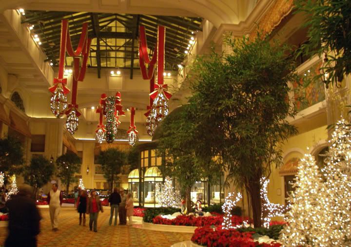 people are walking through the lobby decorated with christmas lights and trees in red, white and green colors