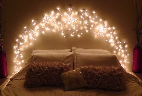 there is a bed with lights on the headboard and pillows in front of it