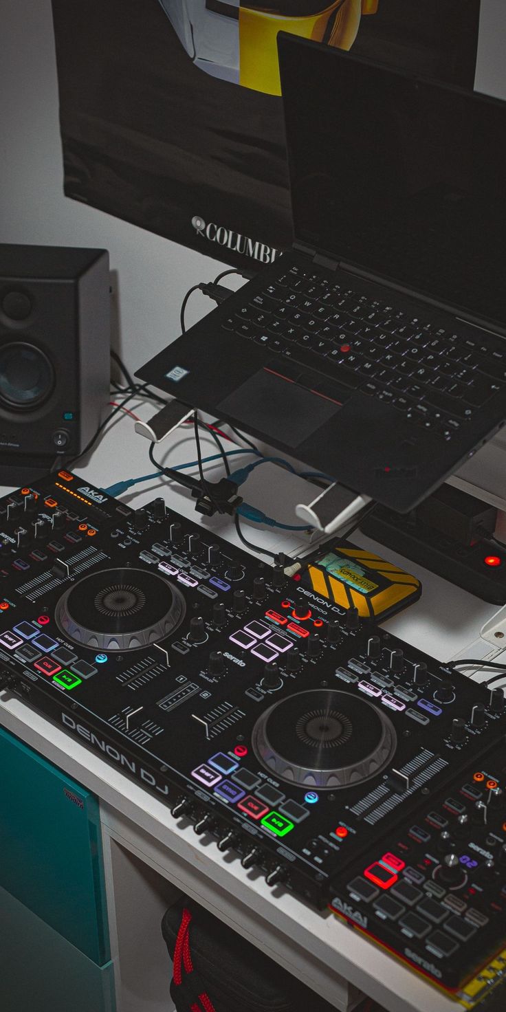 a laptop computer sitting on top of a dj's desk next to a pair of decks