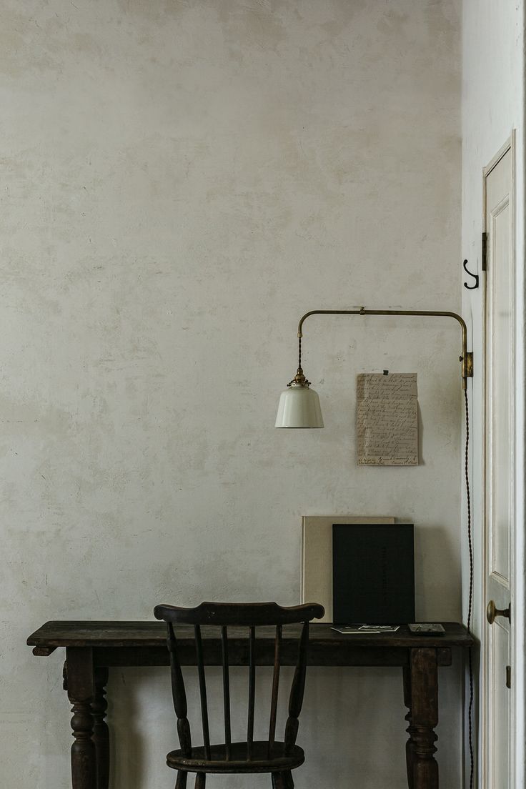 a desk with a laptop computer on top of it next to a chair and lamp