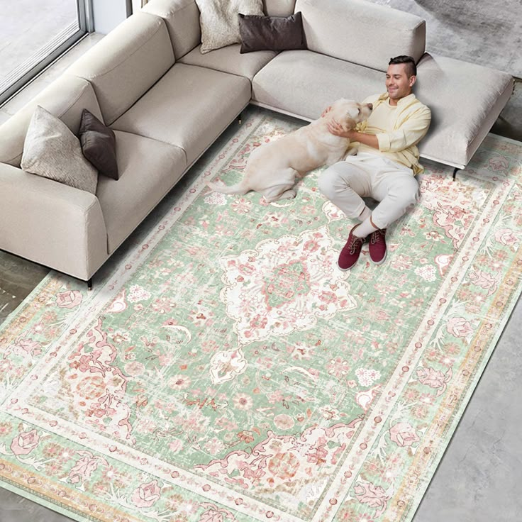 a man laying on top of a large rug next to a couch and a dog