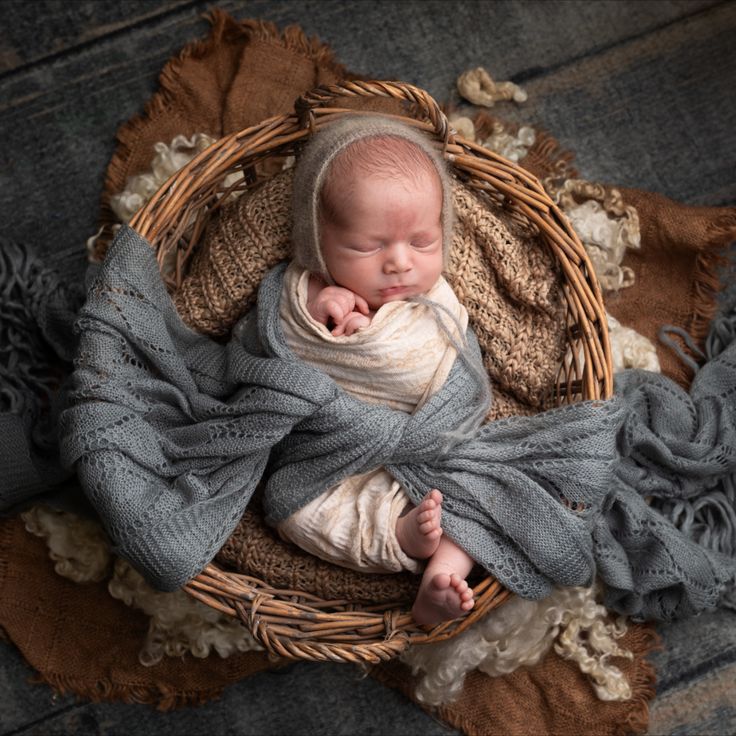 a newborn baby wrapped in a blanket laying on top of a basket