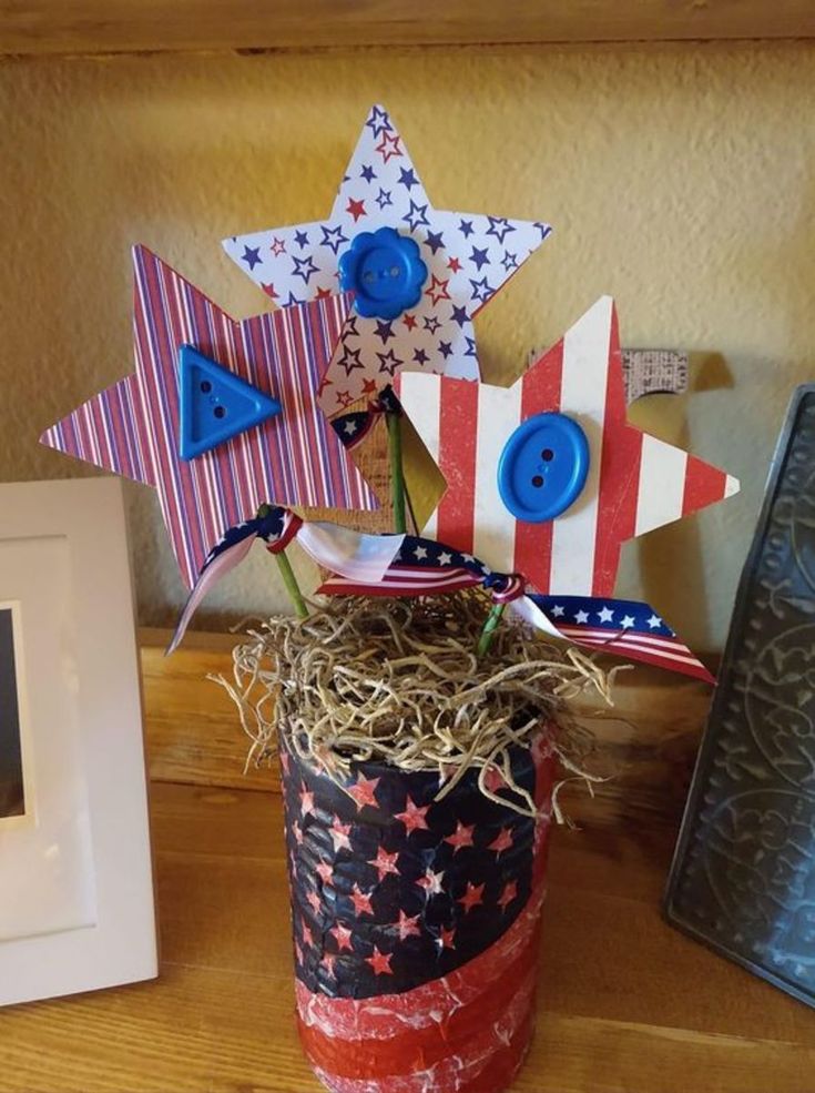 a vase filled with red, white and blue pinwheels on top of a wooden table