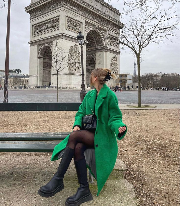 a woman is sitting on a bench in front of the arc de trioe triumph