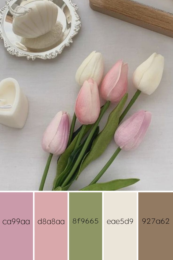 some pink and green tulips are sitting on a table with other items in the background