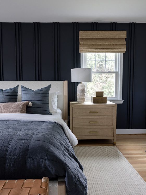 a bedroom with dark blue walls and white bedding