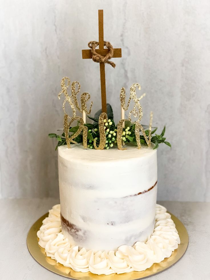 a white cake with gold decorations and a cross on top