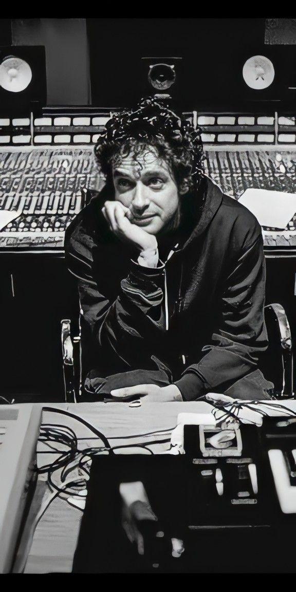 a man sitting at a desk in front of sound mixing equipment with his chin resting on his hand