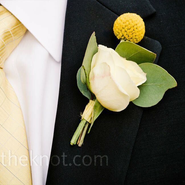 a boutonniere with a white rose and green leaves on the lapel