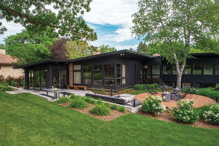 a modern home sits in the middle of a lush green yard