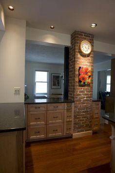 a kitchen with a clock on the brick wall