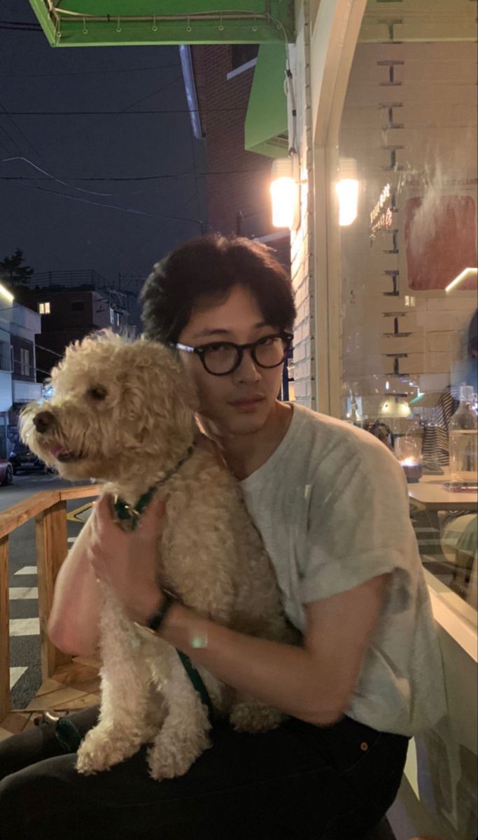 a woman sitting on a bench holding a dog in front of a store at night