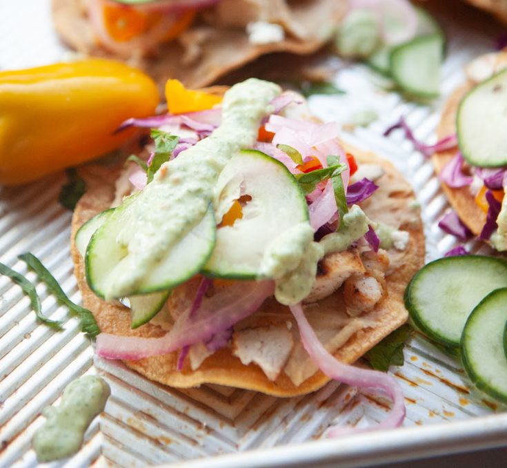 three pita sandwiches with cucumber, red onion and green onions on top