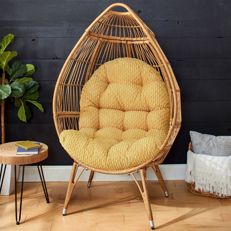 a wicker hanging chair next to a potted plant in a room with black walls