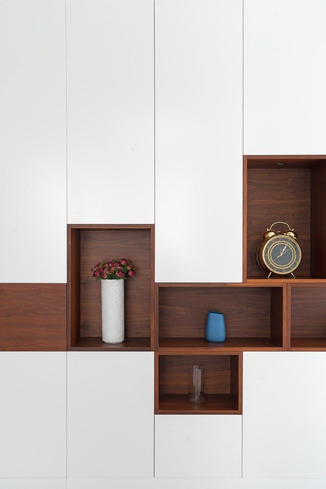 a vase with flowers and an alarm clock sit on shelves