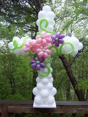 a cross made out of balloons sitting on top of a wooden fence next to trees