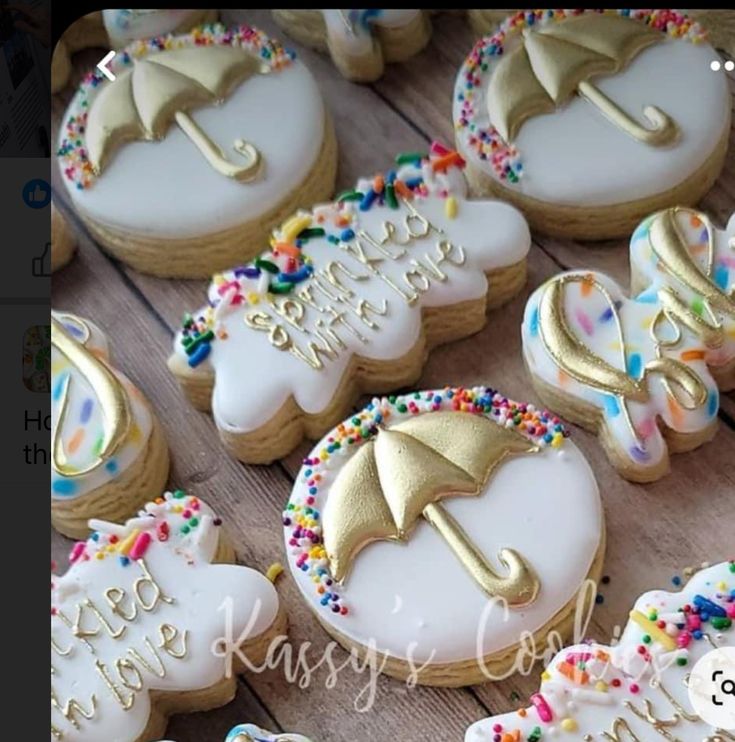 decorated cookies with gold and white icing on a wooden table, one has an umbrella