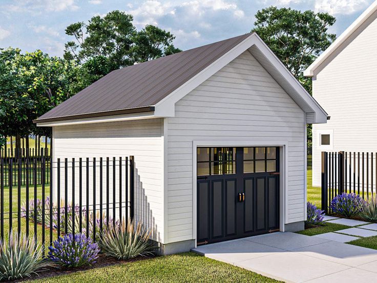 a small white house with a black door and fenced in yard next to it