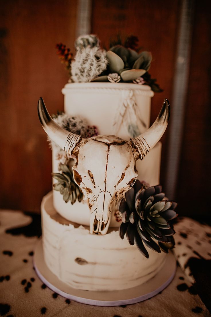 a wedding cake decorated with an animal's skull and succulents on top